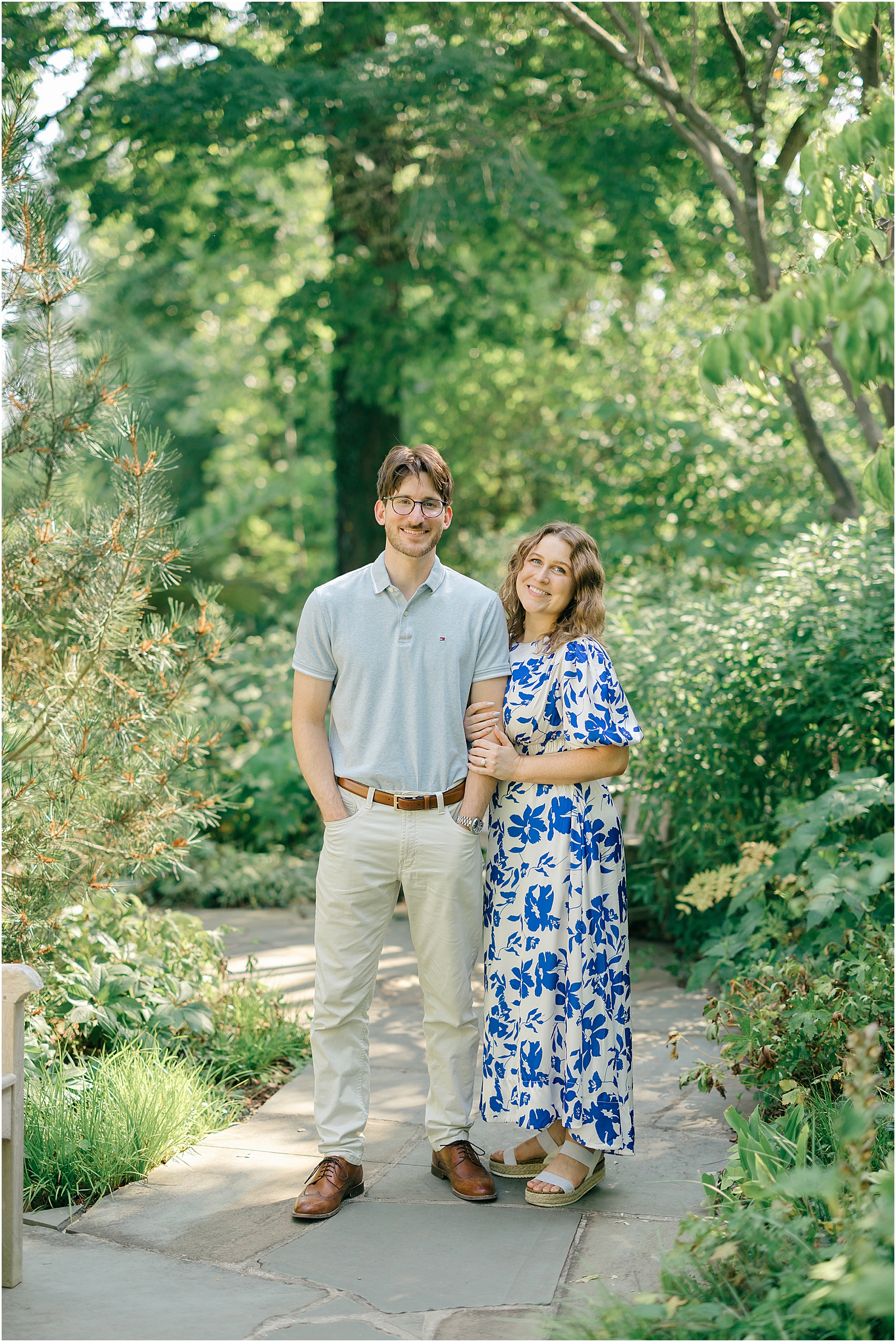 Sam and Kalyn linking arms on a stone garden path during their Maryland engagement session.