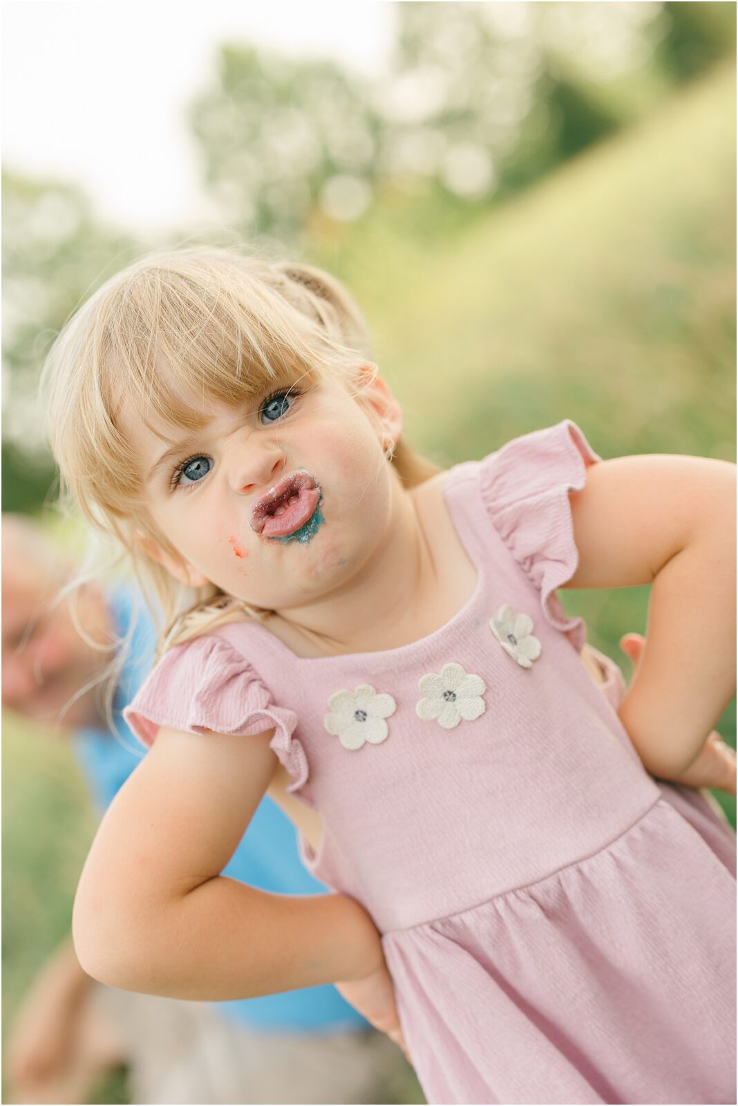 little girl in pink dress making a silly face playing at home during family session