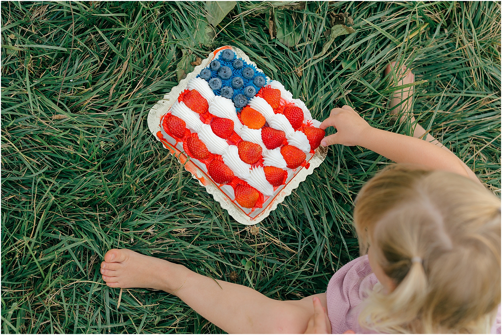 one year old grabbing american flag cake icing for cake smash photos in frederick md