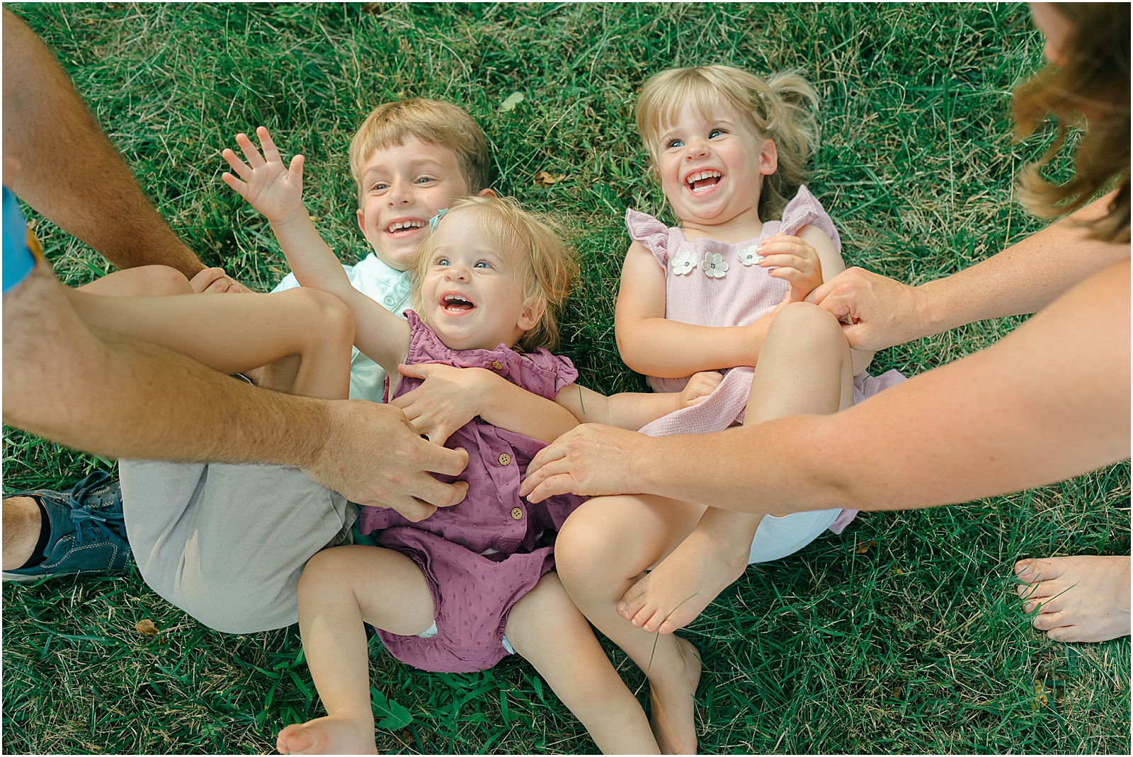 parents tickling three kids laughing in yard at home in frederick maryland
