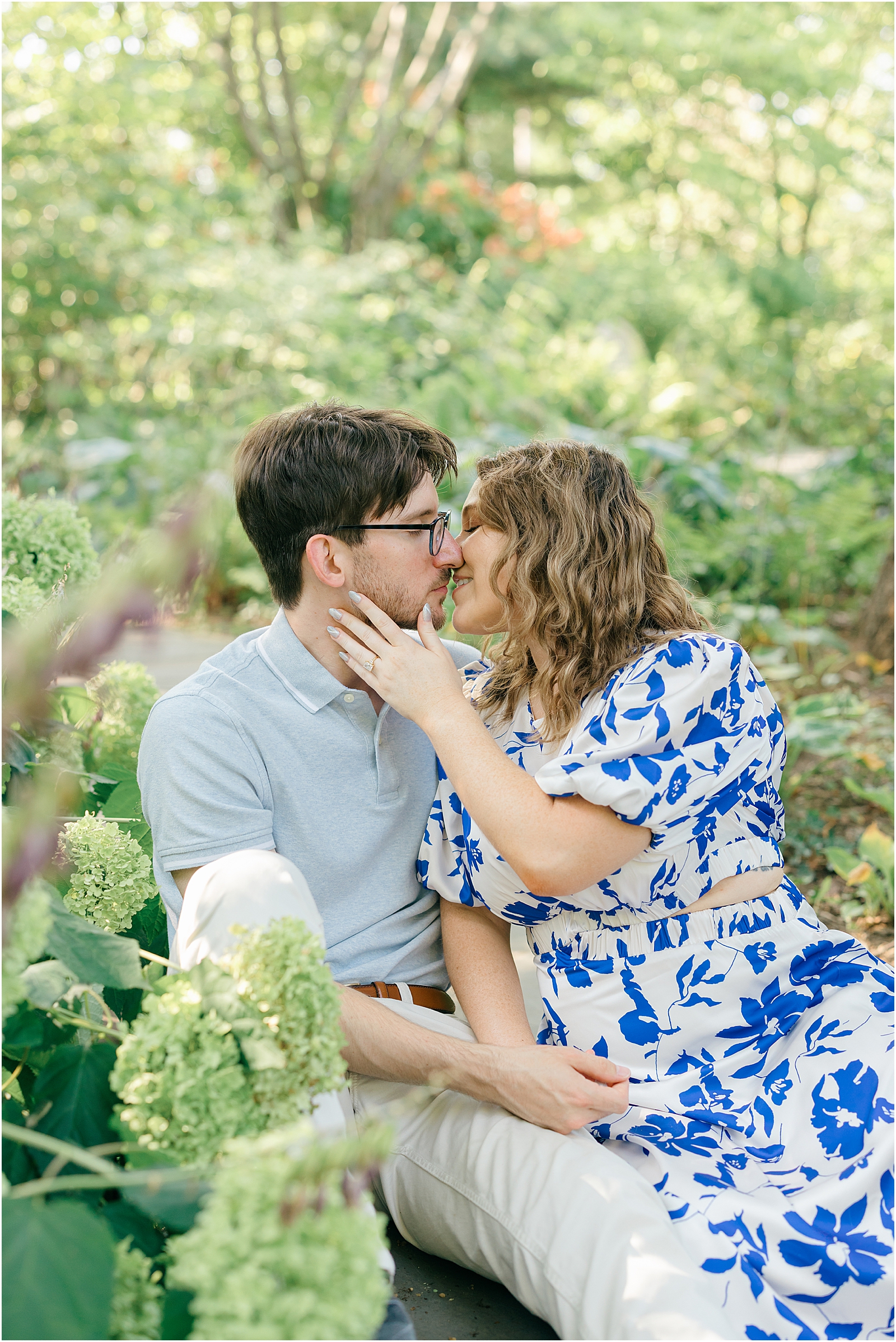 Romantic engagement portraits of Sam and Kalyn beneath a garden arbor and among blooming hydrangeas