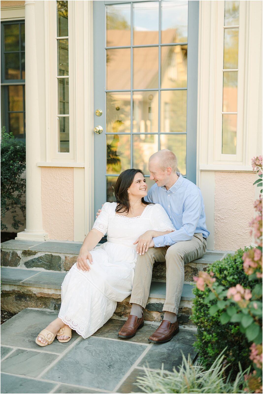couple sitting for engagement portraits on steps at red fox inn in middleburg, virginia.